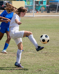 Obraz premium Young athletic teen girl playing in a soccer game