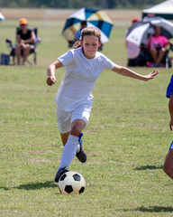 Obraz premium Young athletic teen girl playing in a soccer game