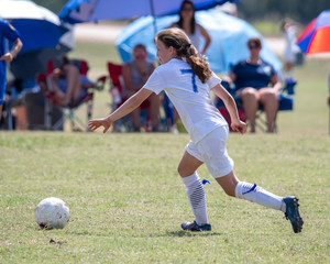 Obraz premium Young athletic teen girl playing in a soccer game