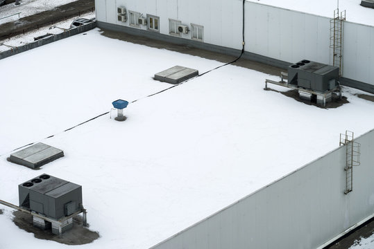The external units of the commercial air conditioning and ventilation systems are installed on the roof of an industrial building. Winter photo.