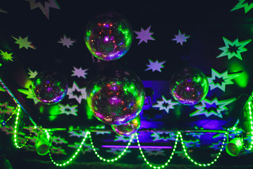 Beautiful shiny balls with colorful lights on ceiling in night club.
