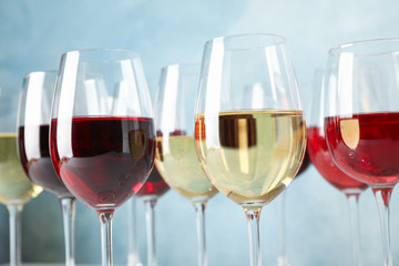 Glasses with wine against light blue background, blurred lights, closeup