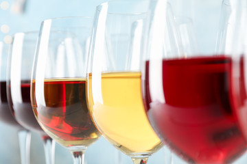 Glasses with wine against light blue background, blurred lights, closeup