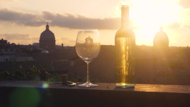 Glass And Bottle Of White Wine In Front Of Panoramic View Of Rome Cityscape From Campidoglio Terrace At Sunset. Landmarks, Domes Of Rome, Italy.