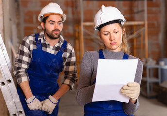 Female foreman checking the work of the builders in house