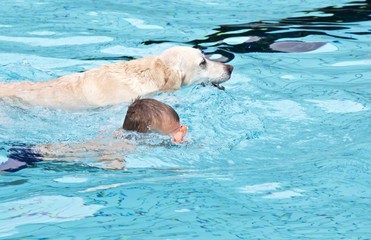 Obraz premium Kind schwimmt mit Hund im Pool