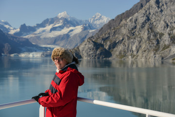 The wonders of nature, a young woman looks  at the camera smiling with a Glacier in the distance. 