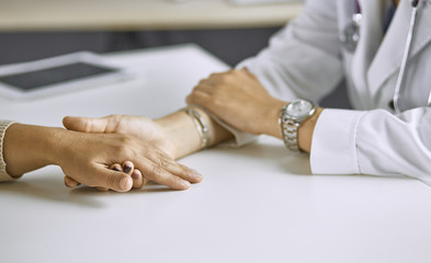 Obraz premium Woman doctor calms patient and holds hand