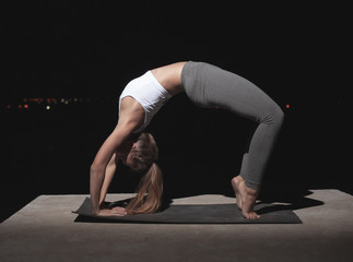 The girl practices yoga at night on the pier. © Tigran Gasparyan