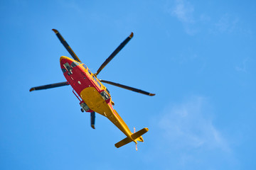 Fototapeta na wymiar Rescue helicopter moving in blue sky with blur propeller. View from bellow