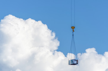 Hook crane with cargo against the sky with white patches