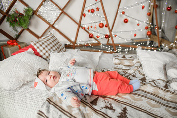 A child from 0 to 1 years old is in bed in a Christmas setting. Happy New Year and Merry Christmas