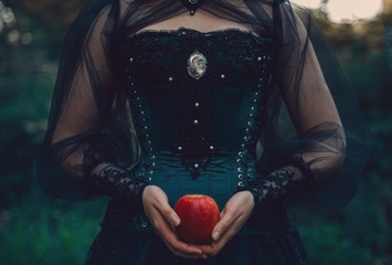 woman in green victorian costume holds red apple