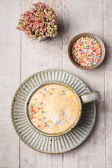 Cappuccino coffee in a mug on a saucer..Flat lay composition of coffee, flowers and sweets, top view, copy space.