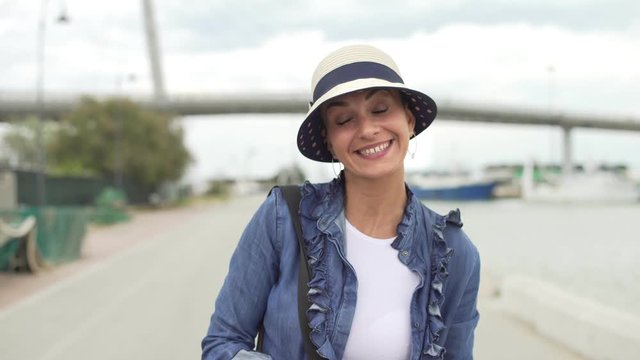 Happy beautiful young woman with a straw hat smiling happily at camera while she's on vacation in spring or summer.