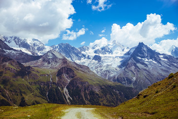 Fototapeta premium Spectacular view on high snowy peaks of the Pennine Alps (Besso, Zinalrothorn) under cloudy sky seen from Sorebois in the summer. Zinal, Val d' Anniviers, Valais, Switzerland