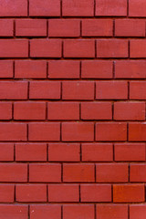 Hauswand aus tiefrotem Ziegelstein mit kleinen Steinen und breiten und tiefen Fugen in gleicher Farbe aus Putz hergestellt