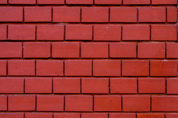 Hauswand aus tiefrotem Ziegelstein mit kleinen Steinen und breiten und tiefen Fugen in gleicher Farbe aus Putz hergestellt
