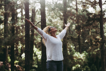 Save the planet for a clean and green better future concept - caucasian people young woman opening arms in the forest to stop deforestation and help the world