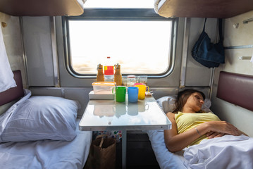 Interior of a reserved seat train car, a girl sleeps on the lower shelf