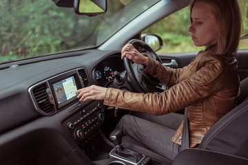 woman in car, checks navigation map on touch screen in car. Lost in finding a route, choosing a route in parking lot, choosing a navigation map, final route. Online application on Internet.