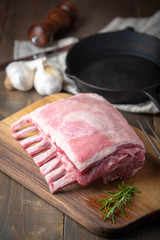 raw lamb rack on wooden cutting board