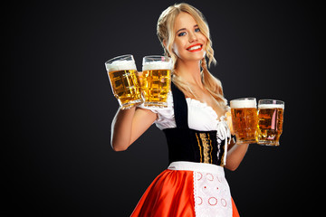 Young sexy oktoberfest girl waitress, wearing a traditional Bavarian or german dirndl, serving two...