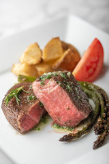 fillet mignon steak with asparagus, tomato and potato on white plate