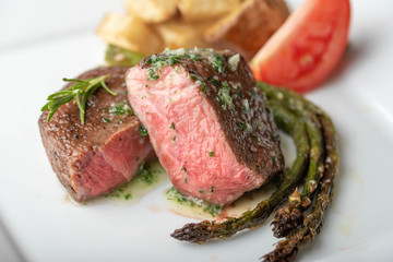 fillet mignon steak with asparagus, tomato and potato on white plate
