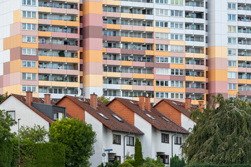Die Fassade eines Wohhochhauses mit Balkonen vor einer Reihenhaussiedlung