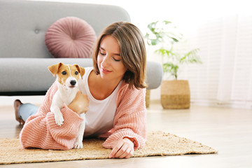 Portrait of young beautiful hipster woman with her adorable four months old jack russell terrier puppy at home in living room full of natural sunlight. Lofty interior background, close up, copy space.