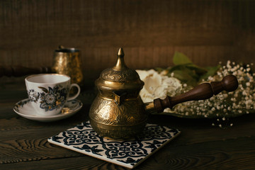 Coffee Turk and a cup of coffee on a ceramic stand on a wooden table.