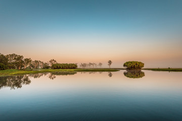 Sunrise at the Yellow Water Cruise, morning mist between trees and smooth water with mirror effect, Kakadu National Park, Northern Territory, Australia © Thomas Jastram