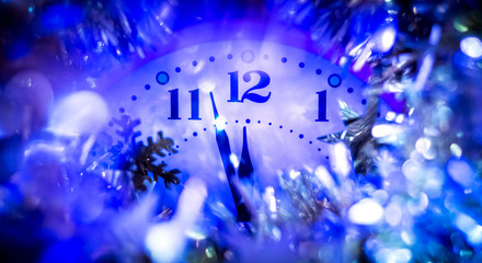 Fototapeta na wymiar The clock hands indicate the approach of the new year. Clock with festive decorations on New Year's night_
