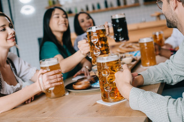 young multicultural friends drinking light and dark beer while celebrating octoberfest in pub
