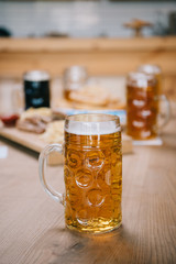 selective focus of mug with lager beer on wooden table in pub