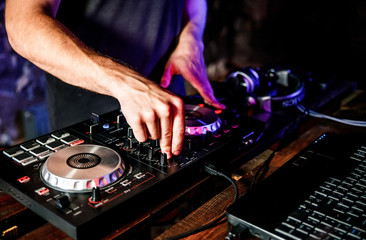 DJ plays live set and mixing music on turntable console at stage in the night club. Disc Jokey...