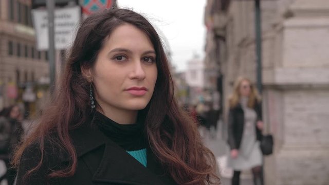 beautiful sensual young woman standing in the street, winking at the camera.