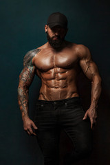 Fototapeta na wymiar Strong and fit man bodybuilder bare-chested in black baseball cap. Sporty muscular guy athlete. Sport and fitness concept. Men's fashion.