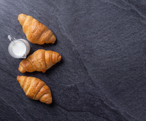 Fresh croissants on a black slate background. Top view Copy space
