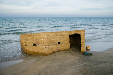 Old war bunker on sandy beach over the sea