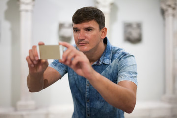 Man taking pictures on phone inmuseum