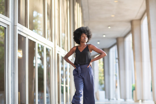 A Young Fashionable Afro-American Woman Walking Down The Street With Her Hands On Her Waist