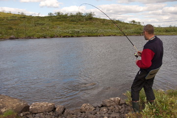 Fisherman catches of a big salmon. Kola Peninsula, Russia.