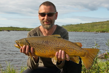 Fisherman hold a big salmon. Kola Peninsula, Russia.