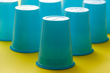 Group of empty blue plastic disposable cups over a yellow background.