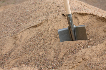 metal shovel stuck in a pile of sand