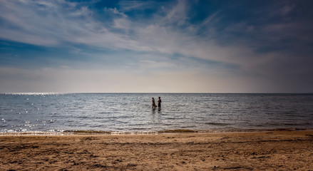Fototapeta na wymiar Bluewater Beach, Township of Tiny, Ontario, Canada - August 10, 2014: Young couple frolic in Georgian Bay on a warm, late summer afternoon.