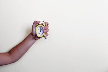 Sad pretty preschool girl holding a yellow alarm clock