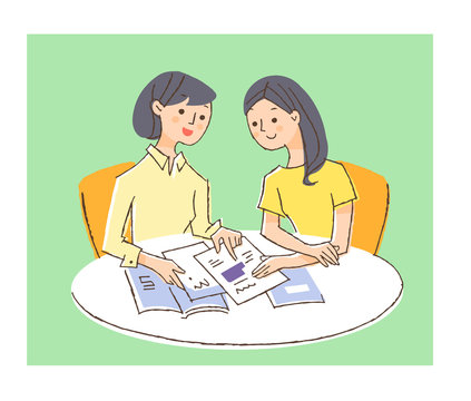 テーブルでパンフレットを見ている若い女性二人